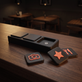 A matte black Social Tap Bar on a cafe counter with one seat empty showing its magnet, and three loose square tiles beside it carrying coral camera, star and cutlery symbols