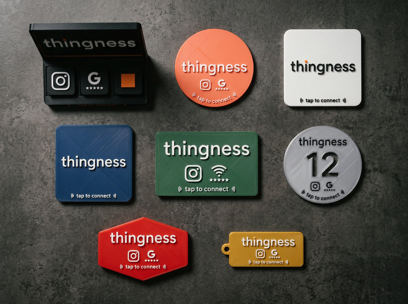 Eight thingness pieces — tap stand, review disc, coasters, wifi plaque, table number, name badge and keyring — each printed in a different filament colour